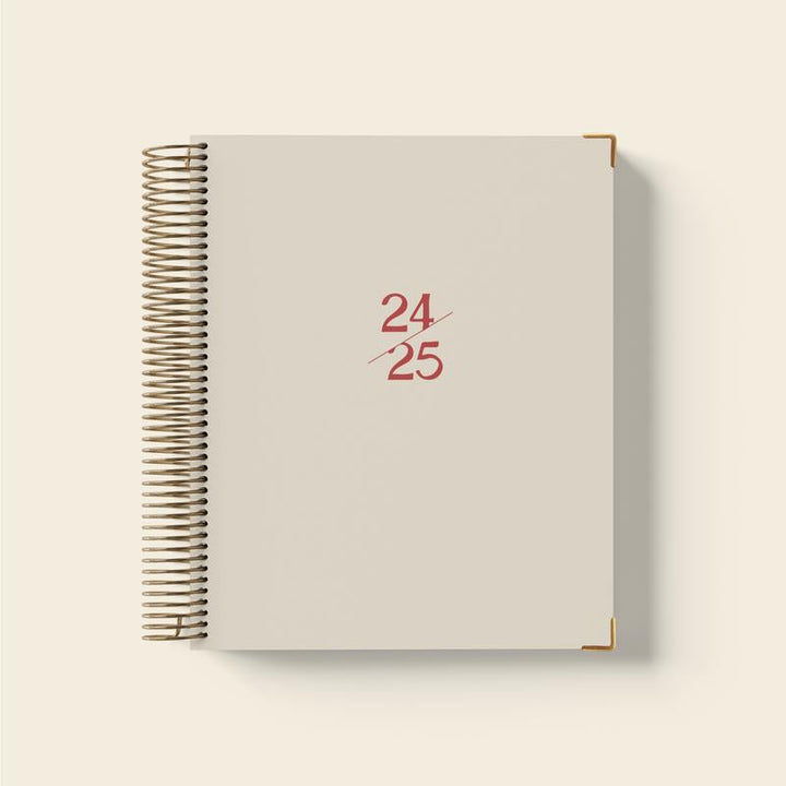 Hand drawing a checkmark in a 2024-2025 planner, signifying task completion.