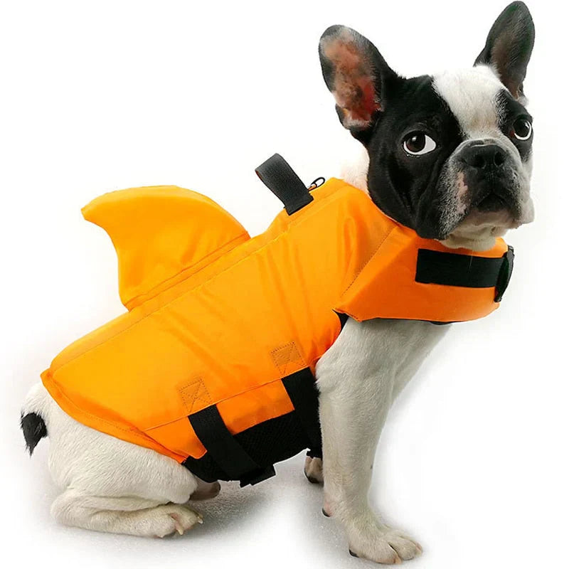 Dog life jacket with shark fin, offering buoyancy and fun for all water activities; bright material, adjustable straps.