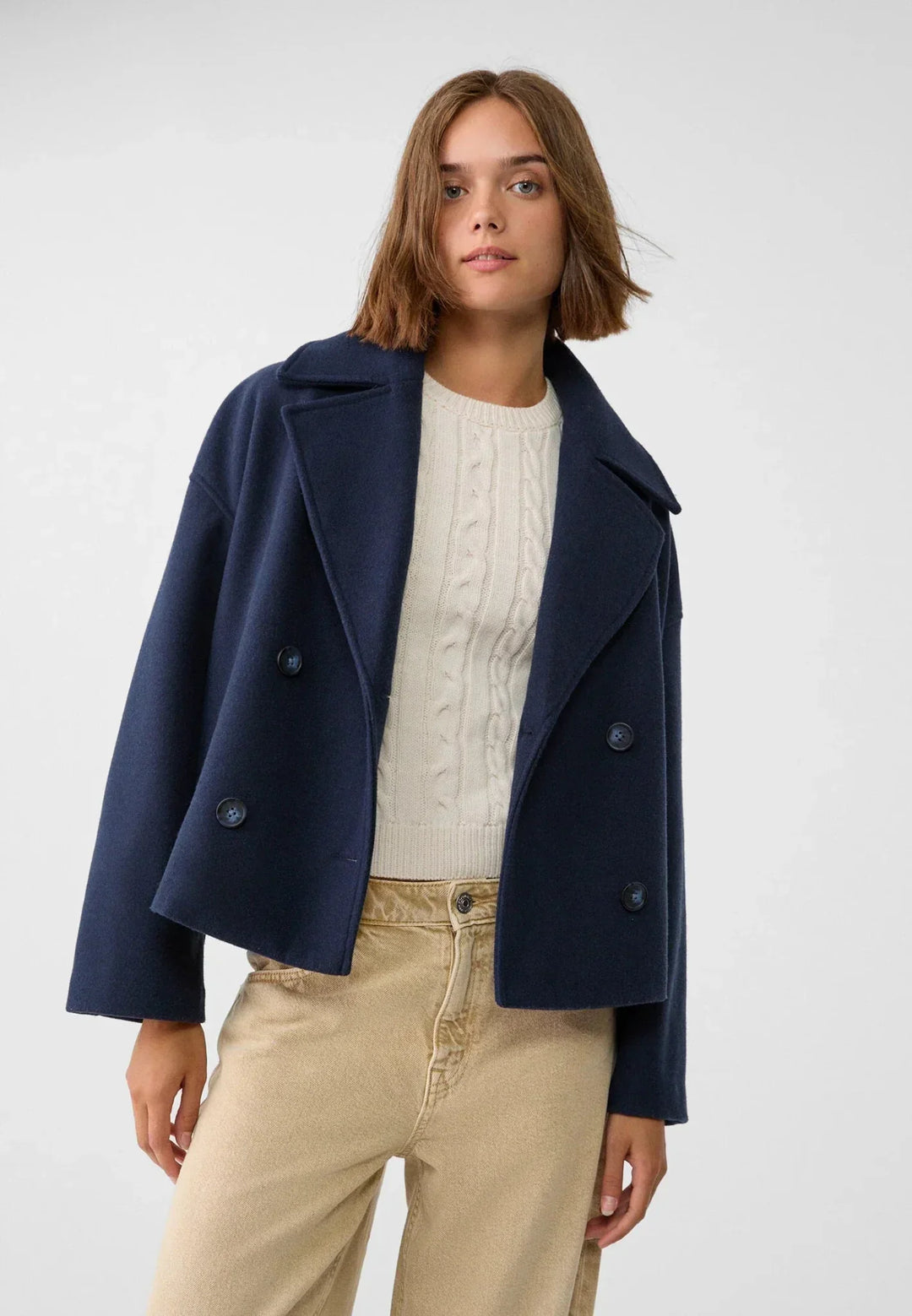 Women's double-breasted cropped jacket, front view featuring sharp lapels, structured design, and chic oversized buttons.