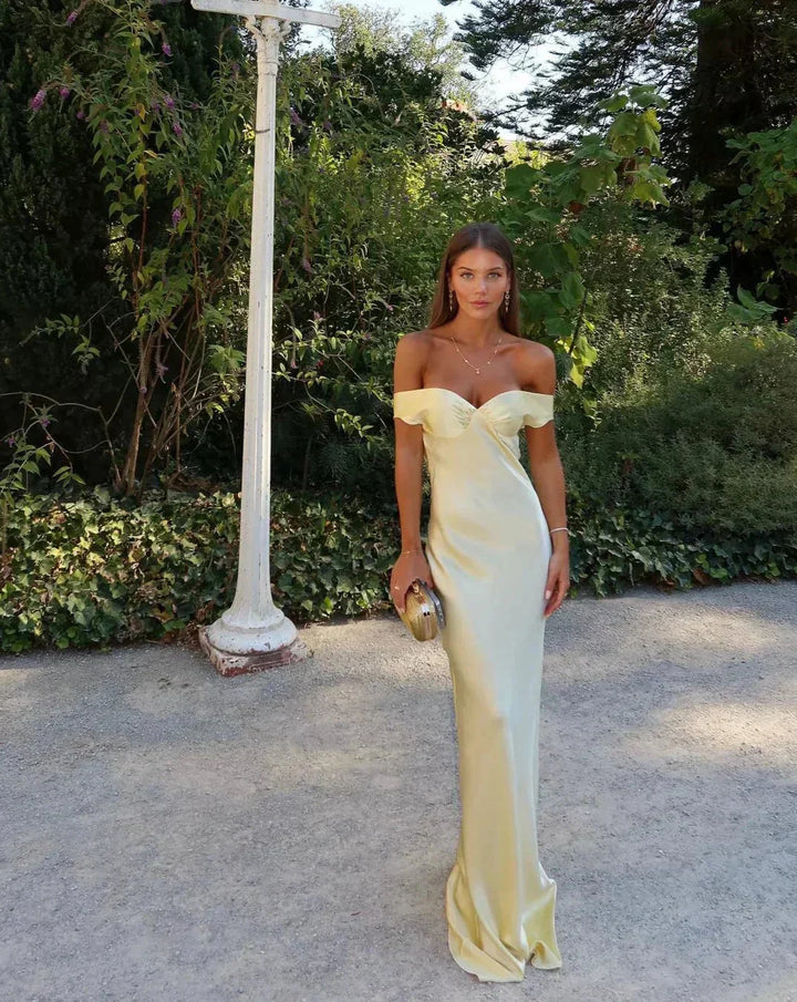 Women's off-shoulder yellow maxi dress with matching clutch; chic design, flowing silhouette, perfect for elegant events.