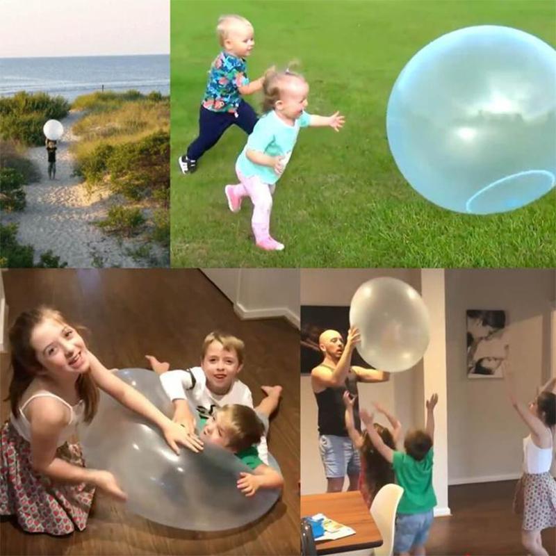 A group of friends laughing while playing with a large inflatable bubble ball on grass.