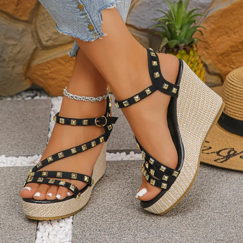 Model wearing black studded platform wedge sandals, styled with a summer dress