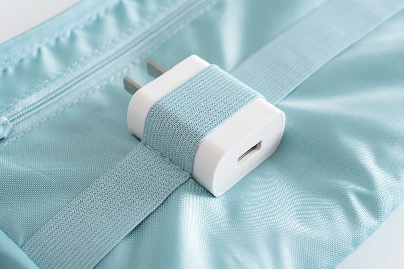 Lifestyle shot: compact waterproof electronics & cable organizer on a suitcase, ready for travel.