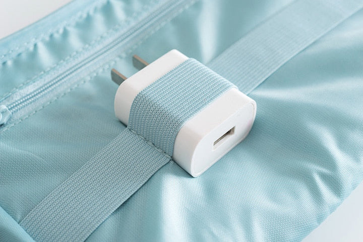 Lifestyle shot: compact waterproof electronics & cable organizer on a suitcase, ready for travel.
