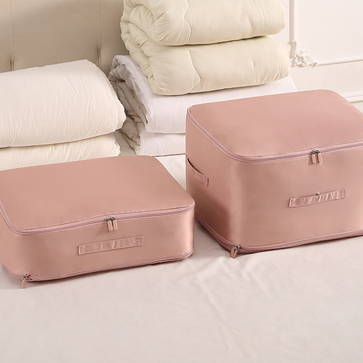 Folded duvet being placed into a compression storage bag, a satin space-saving organizer