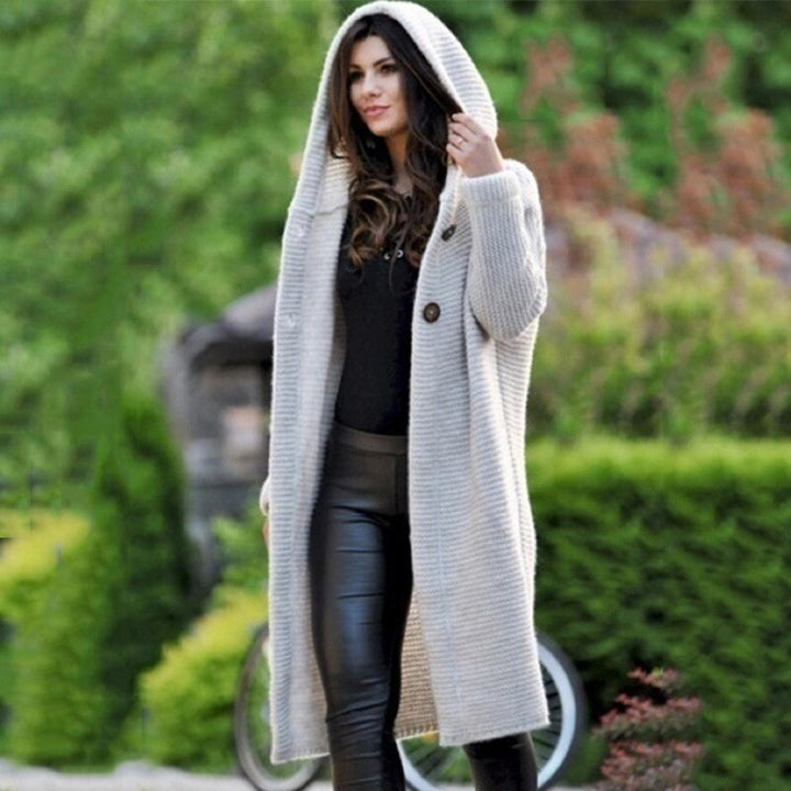 Woman wearing a beige cozy knit hooded maxi cardigan, showcasing its long length and comfortable fit