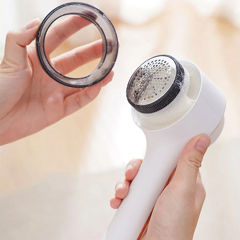 Hand holding Electric Clothes Lint Remover Fabric Shaver, demonstrating its compact size and portability