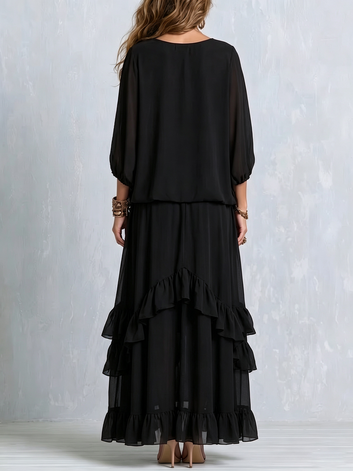 Women's black bohemian two-piece set featuring a flowy tiered maxi skirt & a tassel V-neck top with lantern sleeves.