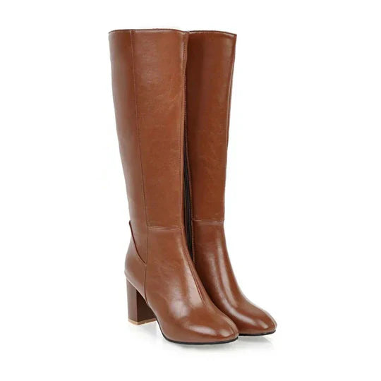 Close-up of the elegant stiletto heel on a women's black knee-high fashion boot.