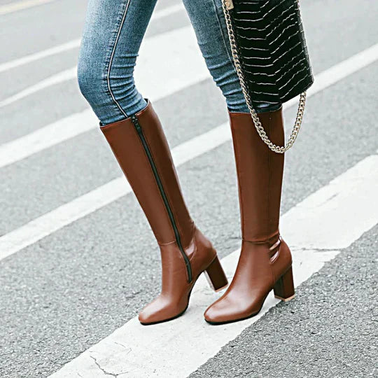 Pair of women's elegant black knee-high boots with stiletto heels, ready for a fashionable outing.