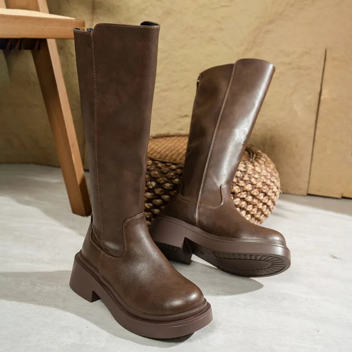 Detail shot of the block heel and sole of a women's elegant leather knee-high boot.