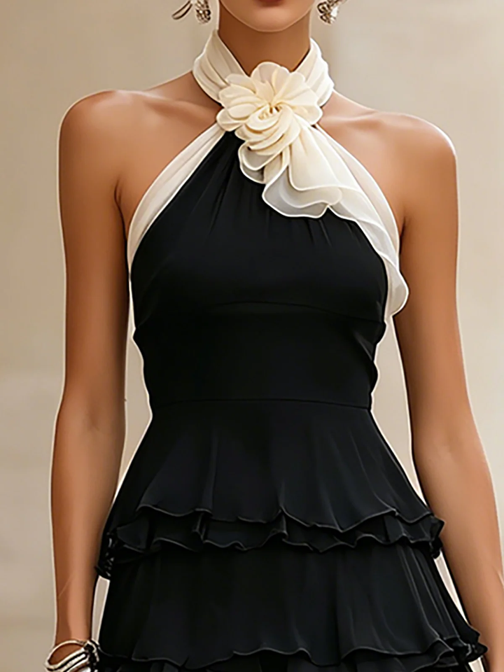 Chic black halter neck mini dress featuring delicate rosette ruffles, ideal for cocktails & special events.
