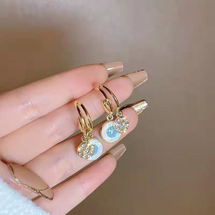 Pair of women's elegant dangle drop earrings featuring a delicate gold leaf sea motif