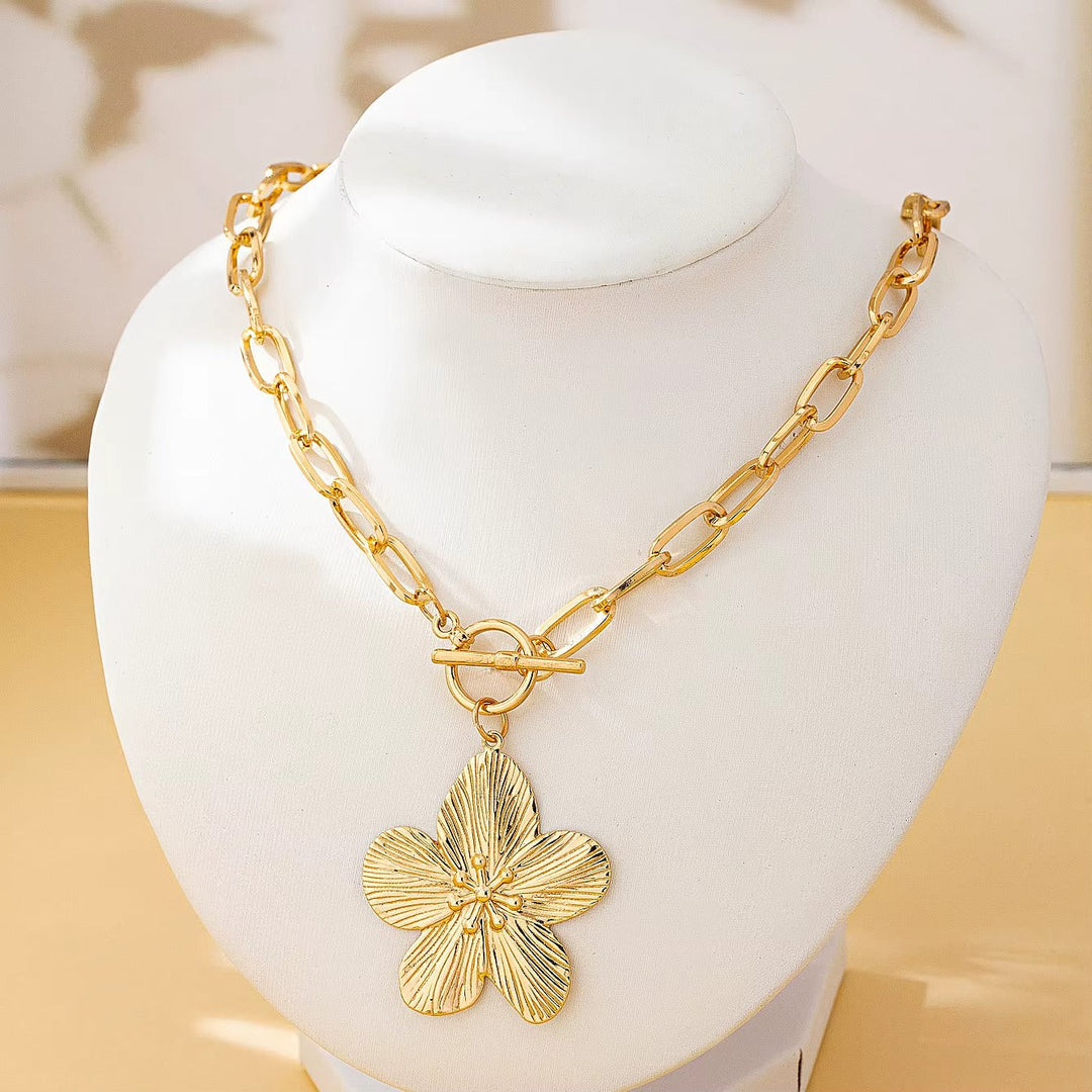 Women's statement textured wisteria flower pendant necklace. Elegant gold-toned floral charm jewelry, vintage style.