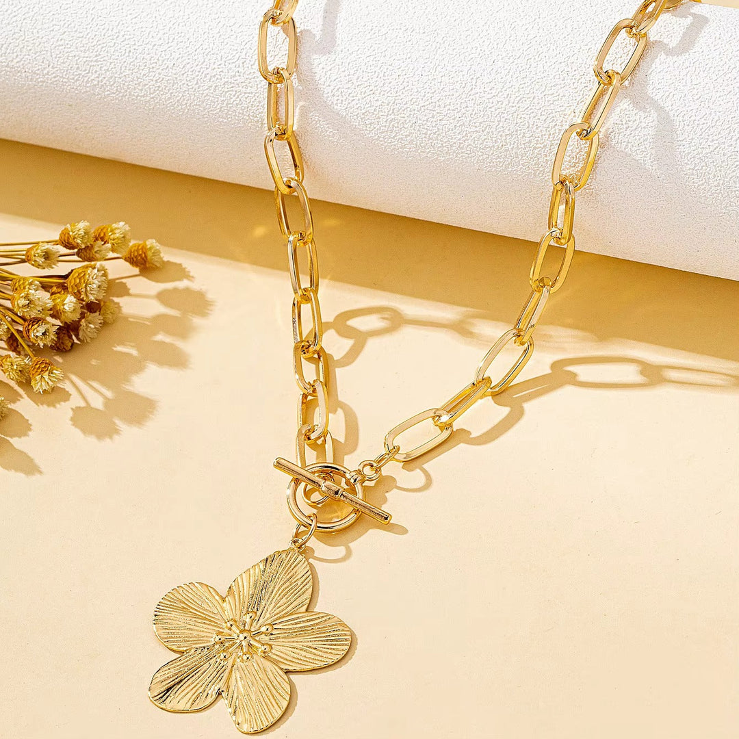 Close-up of a gold-toned textured wisteria flower pendant necklace. Elegant women's floral charm accessory for vintage style.