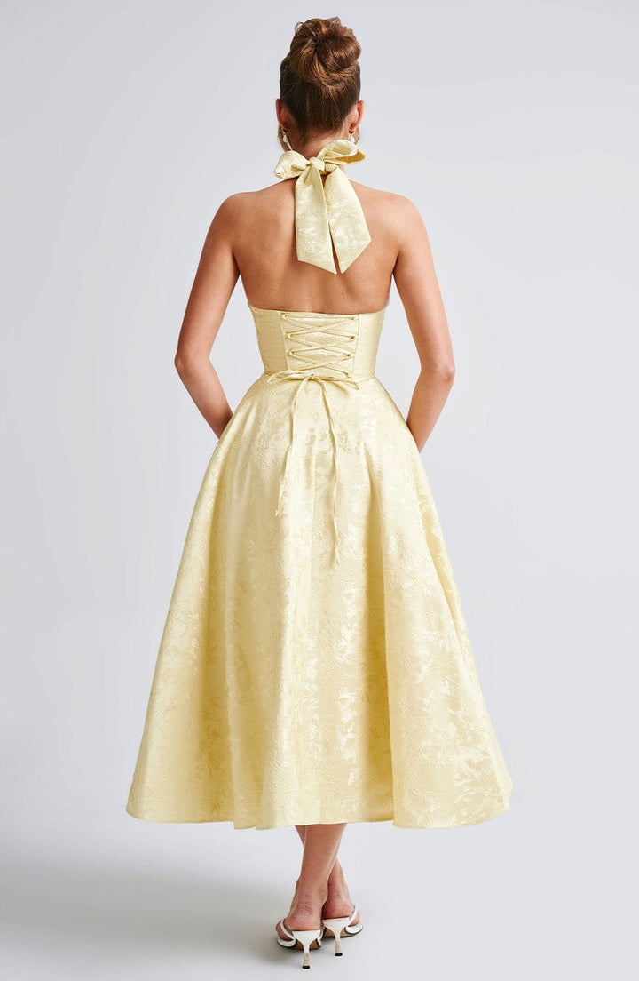 Yellow women's midi dress featuring an elegant halter neck, great for formal gatherings.