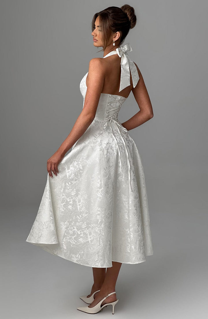 Woman posing in a sophisticated white halter neck midi dress, ideal for formal events.