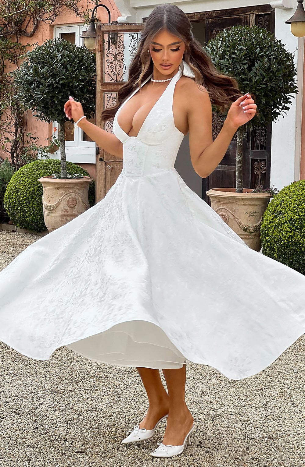 Side profile of a woman wearing a chic yellow halter neck midi dress, elegant and stylish.