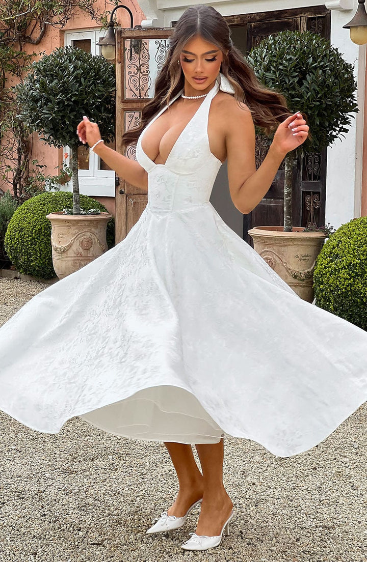 Side profile of a woman wearing a chic yellow halter neck midi dress, elegant and stylish.