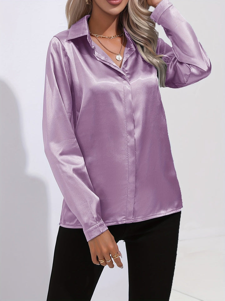 Overhead view of a women's crisp white satin long-sleeve button-down blouse, laid flat to show its design.