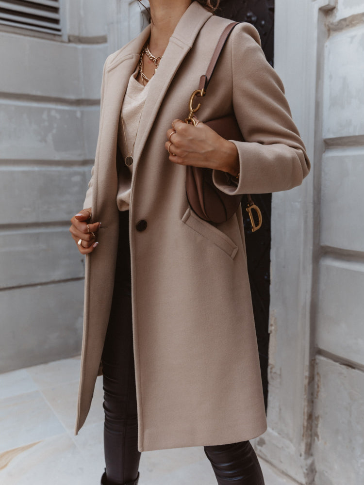 Side view of a woman wearing a chic double-breasted long trench coat in a classic beige.