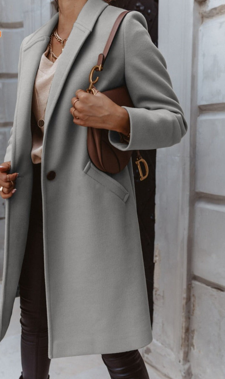 Back view of a women's beige long trench coat, highlighting its elegant double-breasted cut.