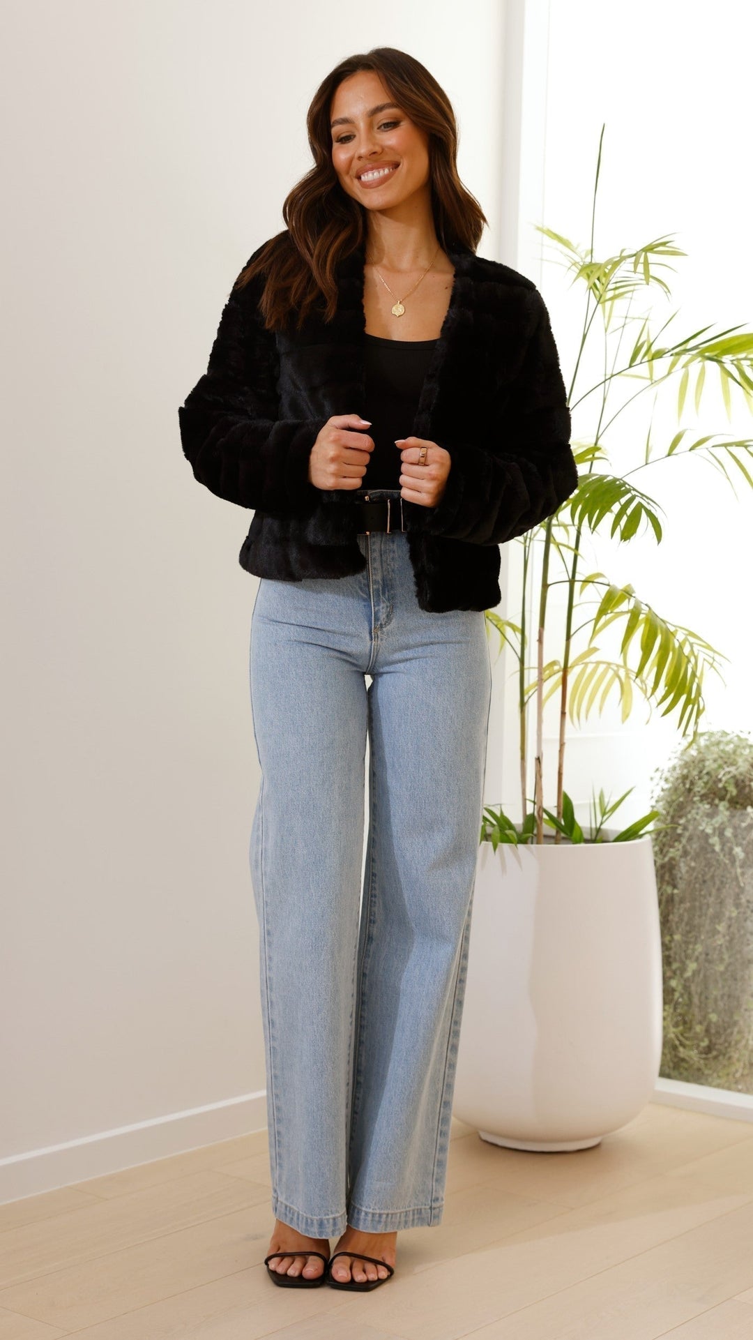 Rear view of a women's elegant cropped faux fur jacket, showcasing its design.