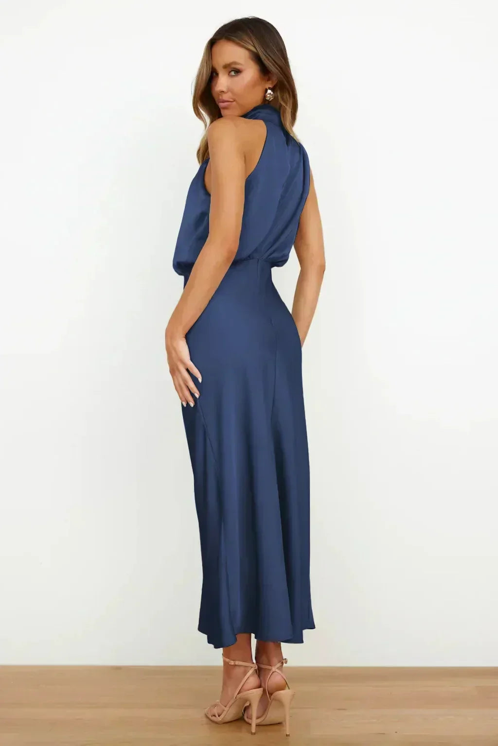 Side profile of a women's elegant halter evening gown, floor-length, showcasing its flowing silhouette.