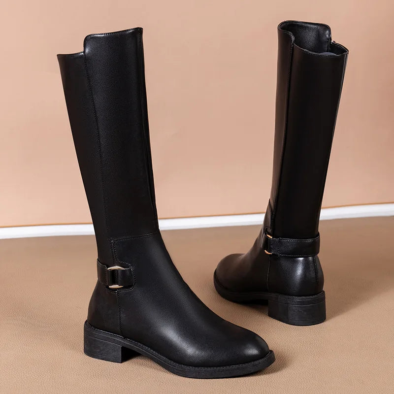 Elegant women's knee-high black leather boots with a silver buckle, perfect for winter fashion