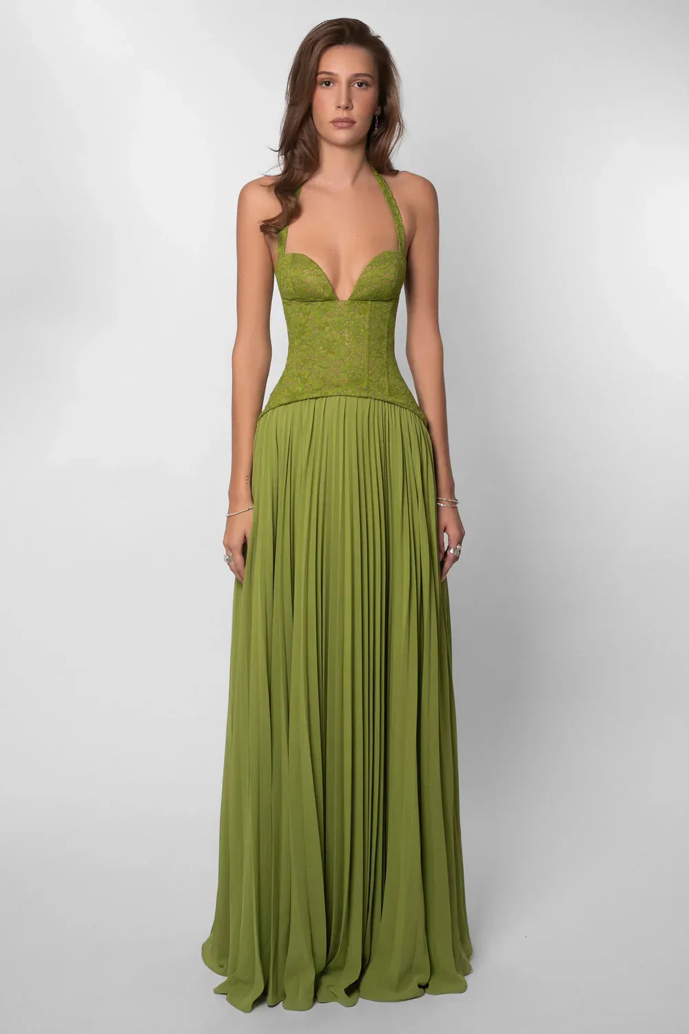 Long green pleated maxi dress for women. Features an elegant corset style bodice and a flowing skirt.