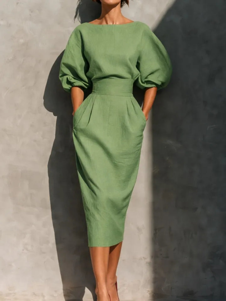 Detailed view of an elegant pleated midi dress for women, showcasing trendy lantern sleeves and a defined cinched waist.