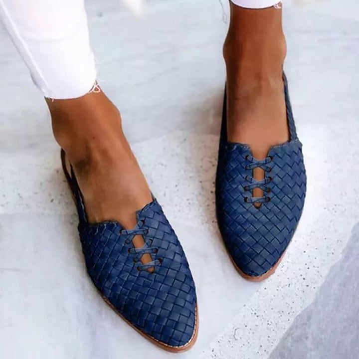 Close-up of textured women's flat loafers. Shows elegant pointed toe and delicate lace-up detail for a chic look.
