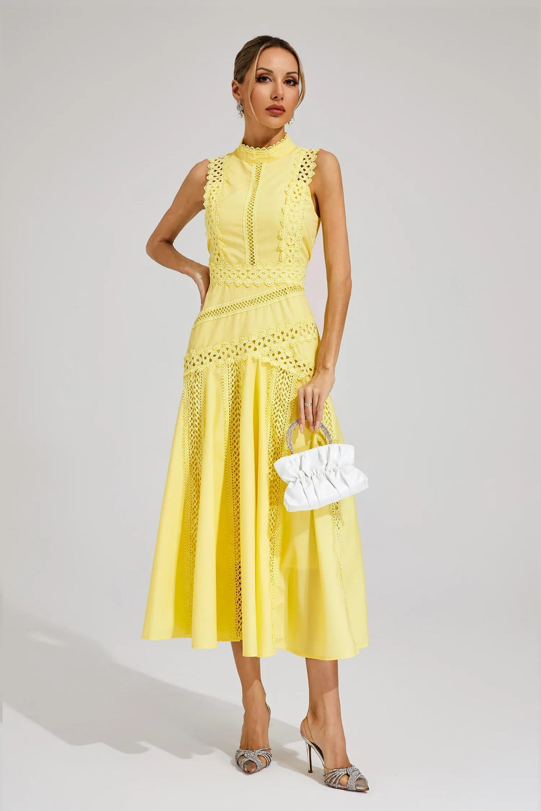 Woman in an elegant sleeveless lace panel midi dress. Chic high neck & flared skirt, ideal for summer party fashion.