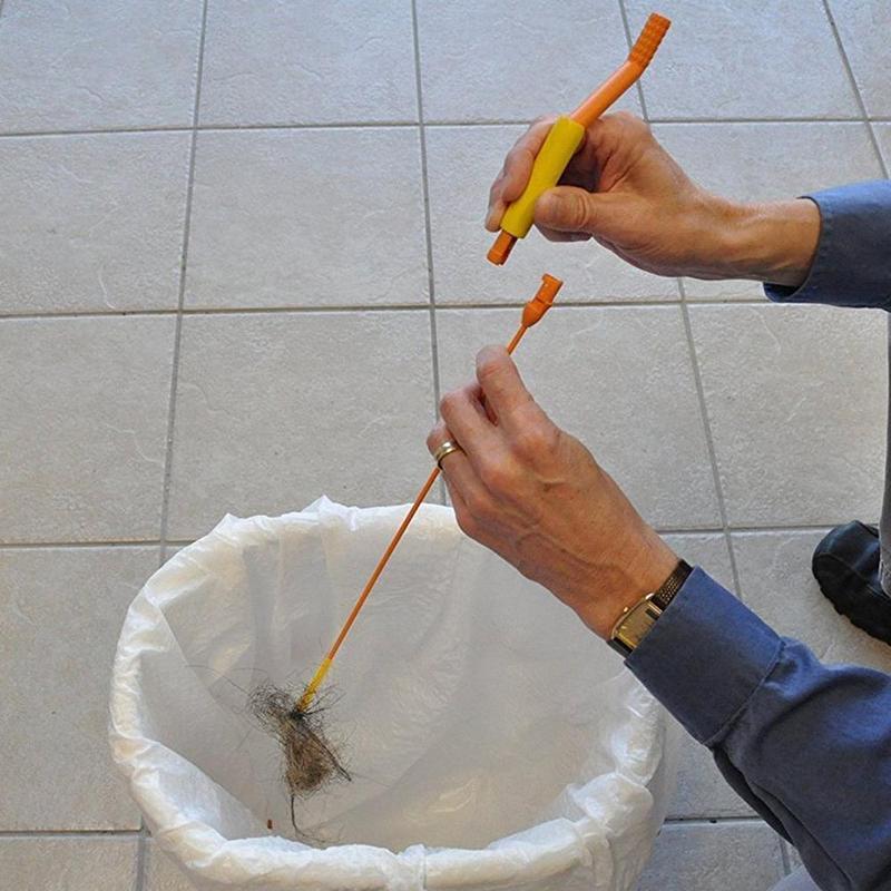 Hand holding a yellow universal drain hair clog remover tool, demonstrating its ease of use
