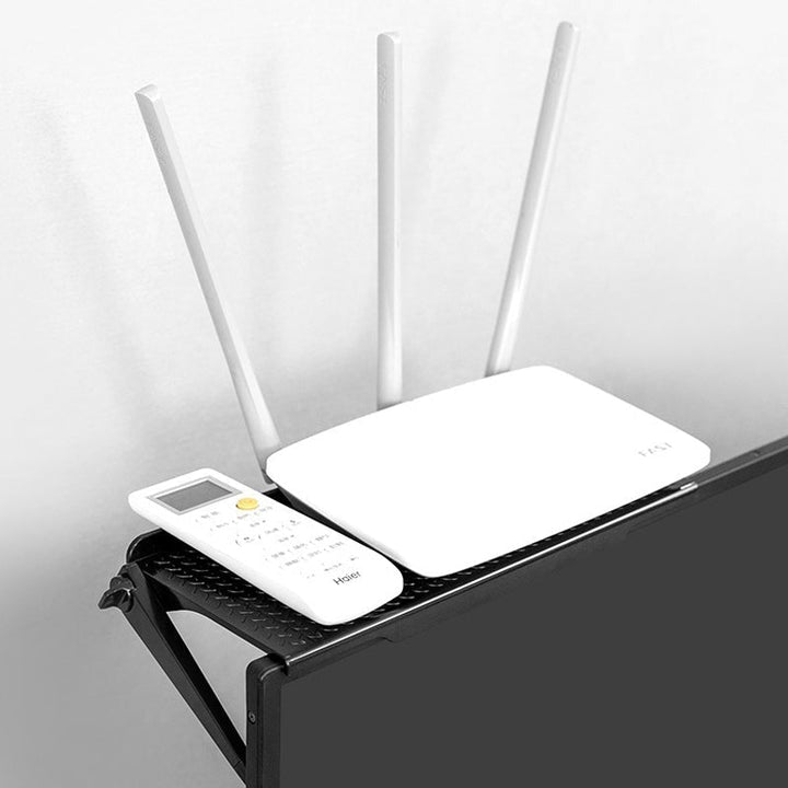 Universal Monitor Top Shelf Organizer supporting a remote control, pen, and small notebook on a home office desk.