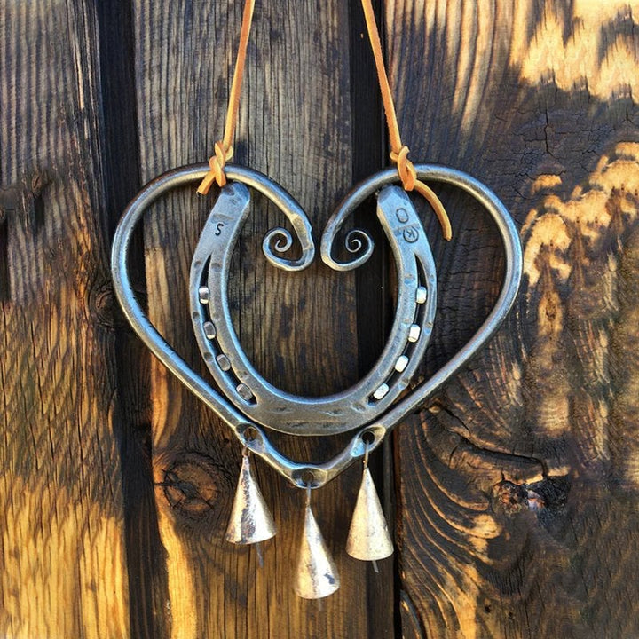 Close-up of a heart-shaped metal wind chime with detailed carvings, perfect for home and garden.