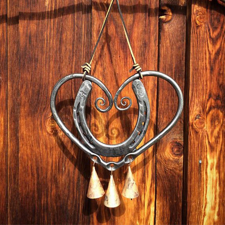 Elegant heart-shaped metal wind chime hanging outdoors, a beautiful gift idea for garden lovers.