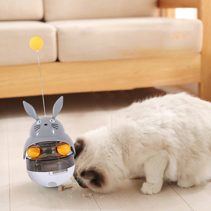 A cat pawing at an interactive treat dispenser tumbler, enjoying playtime
