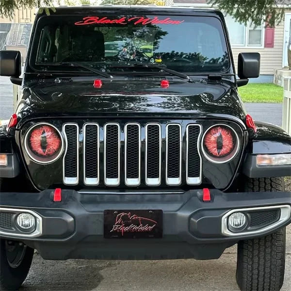 Close-up of a Jeep headlight with the Beast Eyes decal, showing light visibility through perforations