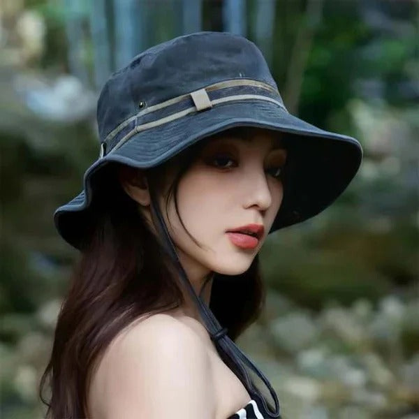 Collapsible black unisex bucket hat with chin strap for travel & hiking, providing sun protection.