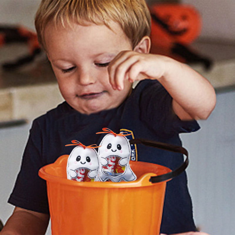 Child reaching into a spooky pumpkin Halloween treat bag, pulling out collected candy enthusiastically