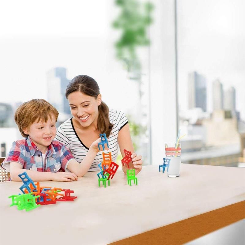 Close-up of children's hands carefully stacking colorful mini chairs in a balancing game