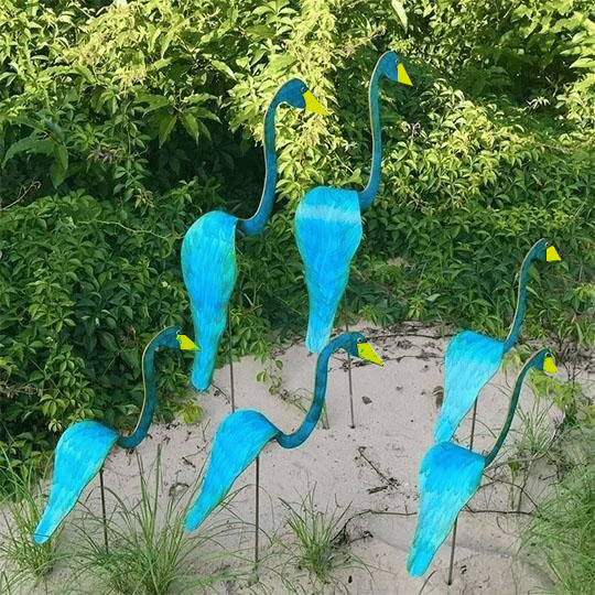 Close-up of a kinetic swirl flamingo wind spinner catching the breeze in a lush garden setting