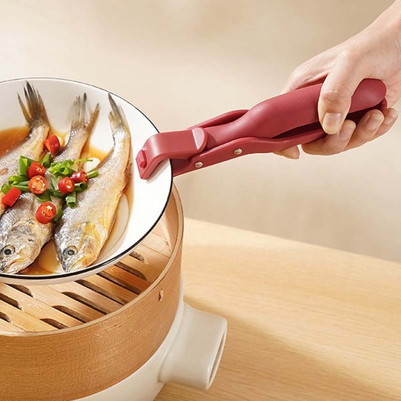 Kitchen anti-scald bowl clip securely gripping a hot ceramic bowl, preventing burns during cooking.