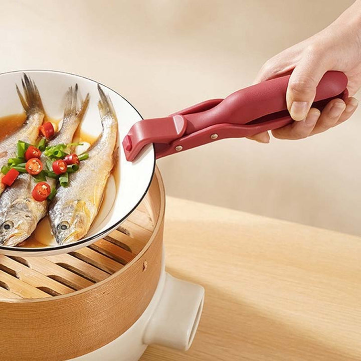 Kitchen anti-scald bowl clip securely gripping a hot ceramic bowl, preventing burns during cooking.