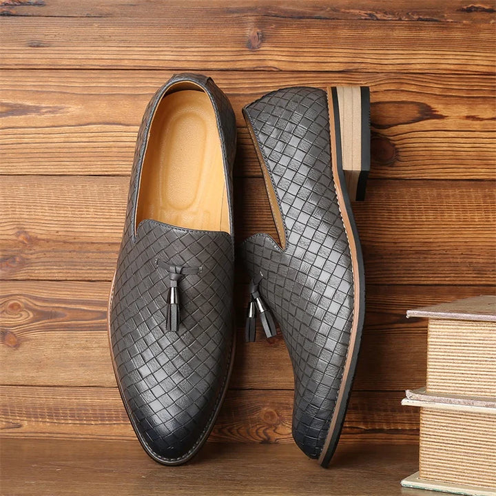 Studio shot of men's black textured tassel loafers, emphasizing their sleek silhouette