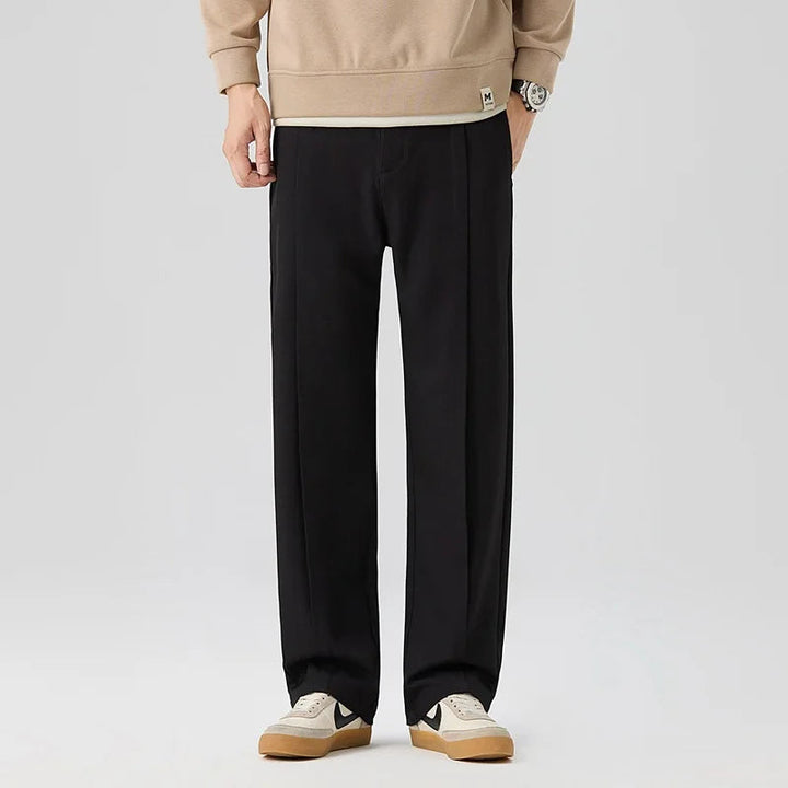 Close-up of men's elegant drape trousers, showing pleats, relaxed fit, & soft fabric for comfort.