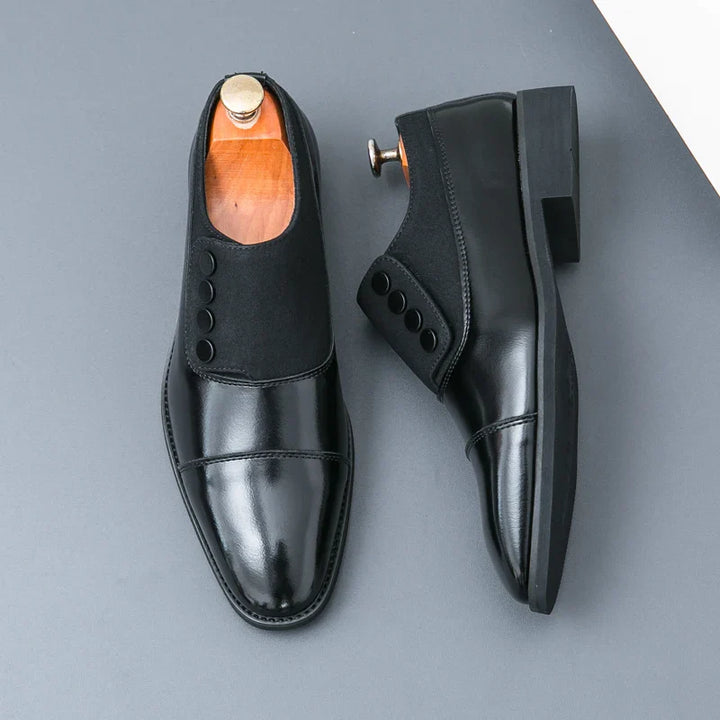 Top-down view of men's black polished leather button loafers, ready for a professional look.