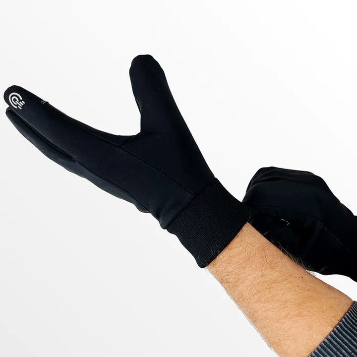 A man wearing black thermal touchscreen gloves, demonstrating smartphone use outdoors in winter weather