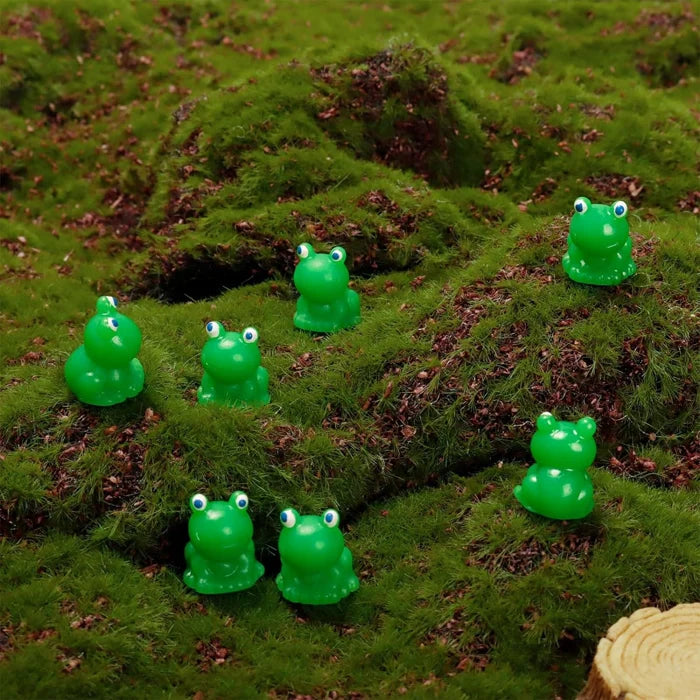 Hand holding a tiny green frog figurine, showing its small size for crafts